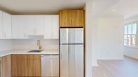 Located at 416 Vine St in Philadelphia's vibrant Old City neighborhood, this thoughtfully designed one-bedroom, one-bathroom unit offers a modern living experience within a compact, efficient floor plan. Light-toned hardwood flooring flows throughout, lending warmth and visual continuity across every room.

The living room is anchored by expansive multi-pane windows that frame views of the surrounding historic streetscape, filling the space with generous natural light. The kitchen is a standout feature, showcasing a clean, contemporary design with two-tone cabinetry — crisp white uppers paired with warm wood-grain lower cabinets — accented by brushed gold hardware. Stainless steel appliances, including a refrigerator, range, microwave, and dishwasher, complete the well-appointed cooking space, all set against a classic white subway tile backsplash.

The bedroom is spacious and bright, featuring large windows with open views that include glimpses of the Philadelphia skyline. Two closets provide ample storage. The bathroom is sleekly finished with a floating wood-tone vanity, white countertop, large-format floor tile, and a glass-enclosed walk-in shower clad in vertical mosaic tile. A dedicated laundry area and utility room add everyday convenience to this polished urban residence.
