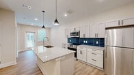 Located in the East Nashville neighborhood at 401 S Fourth St, this well-appointed one-bedroom, one-bathroom unit offers a thoughtfully designed layout across a single floor. Light wood-look flooring flows throughout, creating a cohesive and contemporary aesthetic.

The open-concept kitchen is a standout feature, showcasing white shaker-style cabinetry with matte black hardware, granite countertops, and a bold navy blue subway tile backsplash. A peninsula with pendant lighting provides additional prep space and a casual seating area. Stainless steel appliances, including a refrigerator, range, and microwave, complete the kitchen.

The bedroom is a comfortable, well-sized retreat with a ceiling fan, natural light from a window with outdoor views, and the same warm wood-look flooring found throughout the unit.

The bathroom features matching granite countertops on a white vanity with matte black hardware, a full tub-shower combination with white tile surround, and continued light flooring for a clean, bright finish.

A dedicated laundry room houses a full-size washer and dryer with overhead wire shelving, adding everyday convenience. Recessed lighting throughout the unit maintains a clean, modern look, making this Nashville residence a practical and stylish home.