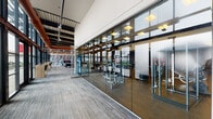 Located at 1523 N Fremont St in Chicago's Lincoln Park area, this single-floor amenity space combines fitness, recreation, and relaxation within a thoughtfully designed, industrial-chic environment. The layout is divided into distinct zones, each serving a specific purpose while maintaining a cohesive aesthetic throughout.

The fitness center is enclosed by full-height glass walls, providing visibility and an open feel while housing an extensive array of equipment. Cardio machines, including treadmills and stationary bikes, line one side of the room, while strength-training machines, free weights, and resistance equipment occupy the rest of the rubber-floored space. Storage racks hold stability balls and additional accessories, and a vending machine offers convenient refreshments.

Adjacent to the fitness area, the recreational game room features soaring ceilings with exposed ductwork and structural beams finished in bold copper tones, adding industrial character. The space includes billiard tables, a shuffleboard table, a putting green, and comfortable leather seating arranged around a wall-mounted television.

A dedicated lounge area with direct outdoor terrace access offers a more relaxed setting, anchored by a linear fireplace set against a dramatic marble-patterned accent wall. Velvet armchairs in deep teal complement leather sofas, creating an inviting atmosphere. Striped carpeting flows throughout the communal zones, unifying the space with a polished, contemporary finish.