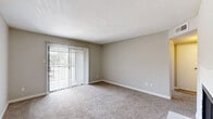 Located at 2400 Briarwest Blvd in Houston, Texas, this single-story, one-bedroom, two-bathroom home offers a well-organized and functional layout across a comfortable footprint. The living room is a welcoming space featuring plush carpeting, neutral-toned walls, and a classic brick-surround fireplace that serves as a natural focal point. A sliding glass door fills the room with natural light and provides a view of the outdoors. The galley-style kitchen is efficiently designed with white cabinetry, light countertops, wood-look luxury vinyl flooring, and black appliances including a range and refrigerator, along with a dishwasher and sink on the opposing wall. The spacious primary bedroom is carpeted and benefits from a ceiling fan, a window with natural light, and direct access to a hallway connecting both bathrooms. The two bathrooms feature light vinyl flooring, white vanities, and shower-tub combinations. A walk-in closet provides generous storage with built-in shelving on both sides. A connecting hallway with wall sconce lighting ties all rooms together, creating a cohesive and practical flow throughout the home.