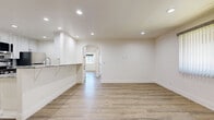 Located at 5513 Fulcher Ave in North Hollywood, this single-story 2-bedroom, 2-bathroom home offers a clean, modern aesthetic throughout. Light wood-tone flooring flows consistently across the living areas and bedrooms, complementing the crisp white walls and bold white baseboards that define the interior's fresh, contemporary character.

The open kitchen is a standout feature, showcasing white shaker cabinetry with matte black hardware, granite countertops with grey veining, a tiled mosaic backsplash, and stainless steel appliances including a gas range. A peninsula with seating potential connects the kitchen seamlessly to the living area, which is bright and open with recessed lighting and large windows dressed with vertical blinds, allowing ample natural light. A built-in bookshelf adds a functional accent to the living room.

Both bedrooms are well-proportioned and bright, each featuring ceiling fans with recessed lighting and windows that offer views of the surrounding neighborhood. The primary bedroom includes a sliding closet door for added convenience.

The two bathrooms are finished consistently, featuring diagonal-set beige tile walls and floors, full soaking tubs with glass slider enclosures, granite-topped vanities, and chrome fixtures — delivering a polished, cohesive look throughout.