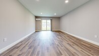 This well-appointed three-floor home offers five bedrooms and three bathrooms across a thoughtfully designed layout. The entry level provides a generous footprint, anchored by a contemporary kitchen featuring slate-blue cabinetry, white quartz countertops, subway tile backsplash, stainless steel appliances, and a bold blue peninsula with pendant lighting overhead. Warm hardwood flooring flows throughout the main living areas, complementing the light, neutral color palette. A sliding glass door leads to a freshly built wooden deck, offering pleasant views of the surrounding greenery and neighborhood. The mid floor is the largest level, providing expansive living space with additional hardwood flooring, recessed lighting, and a wall-mounted mini-split unit for climate control. The upper floor houses the bedrooms, all carpeted for comfort and fitted with built-in wire shelving closets. The primary bedroom offers a comfortable, private retreat. The three bathrooms are clean and modern — one features marble-look tile flooring with a full tub-shower combo and matte black fixtures, while another includes wood-look vinyl flooring and a gray shaker-style vanity with black hardware. Multiple staircases and hallways ensure smooth circulation throughout all three levels.