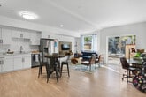 Located at 10568 Gateway Promenade in El Monte, CA, this thoughtfully designed single-floor residence offers a well-organized layout across six distinct areas. The open-concept living and dining space is anchored by light wood flooring, recessed lighting, and large sliding glass doors that flood the interior with natural light while providing direct access to a private outdoor patio. The kitchen is outfitted with white shaker cabinetry featuring matte black hardware, stainless steel appliances including a French door refrigerator with ice dispenser, a gas range, and over-the-range microwave, all complemented by white quartz countertops and a single-basin sink. A dedicated home office or flex space sits adjacent to the patio, featuring vaulted ceilings and additional sliding door access. The bedroom is painted in a calming muted blue tone, with a large window offering outdoor views and ample closet storage. The bathroom presents a dual-sink vanity with quartz countertops, a full-width mirror, and a tiled tub-shower combination. Throughout the residence, light wood flooring and a crisp white palette create a cohesive, modern aesthetic ideal for everyday living.