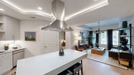 Located near Lakeline Mall in Austin, TX, this 2-bedroom, 2-bathroom residence offers a thoughtfully designed single-floor layout that maximizes both functionality and style. The open-concept kitchen is a standout feature, boasting a large center island with a striking stainless steel range hood, light gray shaker cabinetry, granite countertops, full stainless steel appliance suite including double wall ovens, a microwave, and a French door refrigerator, complemented by a white subway tile backsplash and light hardwood flooring. A tray ceiling with recessed lighting adds architectural depth to the kitchen and living areas. The living room is bright and inviting, featuring large windows dressed in floor-to-ceiling drapes, a contemporary multi-globe chandelier, and an open flow from the kitchen. The primary bedroom offers a comfortable retreat with a ceiling fan and ample closet space. The second bedroom is equally well-sized, with a window and ceiling fan. Both bathrooms are finished with gray shaker vanities, granite countertops, and tiled tub-shower combinations. Two closets provide generous storage throughout the home.
