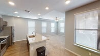Located on S Wren Dr in Gilbert, Arizona, this single-floor home offers a thoughtfully designed layout with modern finishes and a clean, contemporary aesthetic. The open-concept kitchen serves as the heart of the home, showcasing a large granite-topped island with an undermount sink, dark espresso cabinetry extending to the ceiling, a white subway tile backsplash, and stainless steel appliances including a French door refrigerator, electric range, and built-in microwave. Recessed lighting and wood-look flooring complete the kitchen's polished look. The kitchen flows seamlessly into a bright, carpeted living area featuring a tray ceiling, ceiling fan, and multiple windows fitted with white blinds that invite generous natural light. Bedrooms are generously proportioned, with plush carpet, ceiling fans, tray ceilings, and abundant natural light from well-placed windows. The primary bathroom is elegantly appointed with dark cabinetry, granite countertops, dual undermount sinks, and wood-look flooring, while a secondary bathroom offers a tiled tub-shower combo with dark cabinetry accents. A carpeted staircase with a wood handrail connects to additional areas of the home. Neutral gray tones and clean white trim throughout create a cohesive, move-in-ready atmosphere.