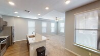 Located on S Wren Dr in Gilbert, Arizona, this single-floor home offers a thoughtfully designed layout with modern finishes and a clean, contemporary aesthetic. The open-concept kitchen serves as the heart of the home, showcasing a large granite-topped island with an undermount sink, dark espresso cabinetry extending to the ceiling, a white subway tile backsplash, and stainless steel appliances including a French door refrigerator, electric range, and built-in microwave. Recessed lighting and wood-look flooring complete the kitchen's polished look. The kitchen flows seamlessly into a bright, carpeted living area featuring a tray ceiling, ceiling fan, and multiple windows fitted with white blinds that invite generous natural light. Bedrooms are generously proportioned, with plush carpet, ceiling fans, tray ceilings, and abundant natural light from well-placed windows. The primary bathroom is elegantly appointed with dark cabinetry, granite countertops, dual undermount sinks, and wood-look flooring, while a secondary bathroom offers a tiled tub-shower combo with dark cabinetry accents. A carpeted staircase with a wood handrail connects to additional areas of the home. Neutral gray tones and clean white trim throughout create a cohesive, move-in-ready atmosphere.