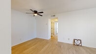This single-floor residence offers a well-organized layout designed for comfortable everyday living. The interior is finished with a clean, neutral palette of crisp white walls and light-toned flooring that flows throughout the main living areas, creating a bright and airy atmosphere. Ceiling fans are installed in multiple rooms, providing both functional airflow and subtle visual interest.

The living area is generously proportioned, featuring light wood-style flooring and a ceiling fan, with an open passage connecting to additional rooms down the hall. Natural light filters in through windows fitted with blinds, lending warmth to the space.

The galley-style kitchen is efficiently laid out with white cabinetry on both sides, light countertops, a classic subway tile backsplash, and black appliances including a range, refrigerator, and dishwasher. The light flooring continues here, complementing the clean, modern aesthetic.

The bedrooms are carpeted for comfort, each equipped with ceiling fans and windows that allow natural light and outside views. The rooms offer a calm, restful environment with ample wall space.

The bathroom is finished with white subway tile surrounding a full soaking tub and shower combination, paired with light wood-style flooring, contributing to the home's consistent, cohesive design throughout.