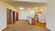 Located at 5317 South Palouse in Spokane, WA, Unit F248 is a single-floor residence featuring a thoughtfully designed, open-concept layout. The kitchen is well-appointed with warm honey-toned wood cabinetry, a dual-basin sink, tile backsplash, and a full suite of white appliances including a refrigerator, range, and built-in microwave. A peninsula counter with a laminate top separates the kitchen from the adjoining living area, making it ideal for both cooking and entertaining. The living space is generously proportioned with plush carpeting and an exterior door that opens to an outdoor area, accompanied by large windows that allow ample natural light to fill the room. Throughout the unit, warm wood-tone trim and baseboards provide a cohesive design aesthetic. The flooring transitions between hardwood-style planks in the kitchen and entryway areas to carpet in the living and bedroom spaces. Two bathrooms serve the unit: one features a full tub-shower combination with hardwood-style flooring, and the other offers a vanity with generous counter space and tile flooring. Additional highlights include vaulted ceiling sections that enhance the sense of height and openness, a dedicated utility panel, and a layout that provides clear separation between living and private spaces.