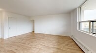 Located on the third floor at 4222 Bathurst Street in Toronto's north end, this 2-bedroom, 1-bathroom unit offers a well-designed layout with consistent, modern finishes throughout. Light oak-toned laminate flooring runs continuously across the entire unit, creating a cohesive and clean aesthetic complemented by crisp white walls.

The kitchen is thoughtfully appointed with white shaker-style cabinetry, white subway tile backsplash, dark countertops, a double stainless steel sink, and a full suite of stainless steel appliances including a refrigerator, stove, and built-in microwave. A hallway connects the kitchen to the bright living room, which features a large picture window offering views of the tree-lined street and neighbourhood beyond, along with a baseboard heating unit.

Both bedrooms are comfortably proportioned and filled with natural light through sizable windows that overlook the surrounding residential neighbourhood. The primary bedroom includes a built-in double sliding-door closet, providing generous storage. The second bedroom also benefits from natural light and baseboard heating.

The bathroom features full white subway tile surrounding a soaker tub and shower combination, with a window above providing natural ventilation. The unit is accessed via a hallway entry, and the building is situated adjacent to open green space.