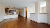 This single-floor residence offers a contemporary open-concept layout where rich dark hardwood flooring flows throughout the main living areas, creating a warm yet modern aesthetic. An entry hallway flanked by doors leads into the heart of the unit, revealing a spacious living area anchored by large windows with vertical blinds that invite abundant natural light and provide outdoor views of the surrounding neighborhood.

The kitchen is a standout feature, outfitted with dark espresso-toned cabinetry, light quartz countertops, a white subway tile backsplash, and a full suite of stainless steel appliances including a refrigerator, range, microwave, and dishwasher. Pendant lighting above the peninsula counter adds a refined finishing touch, while the open layout allows seamless interaction between the kitchen and living space.

The bedroom features soft wall-to-wall carpeting and a generously sized window that draws in natural light. The bathroom is well-appointed with a dark vanity, quartz countertop, a walk-in glass-enclosed shower, and hardwood-style flooring. A dedicated laundry area accommodates a full-sized washer and dryer, adding everyday convenience to this thoughtfully designed residence.