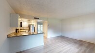 Located at 7633 NW 42nd Pl in Sunrise, Florida, this single-story space presents a clean, move-in-ready interior with a cohesive design aesthetic carried throughout. Light wood-style flooring runs continuously across the main living areas and bedrooms, lending a bright, airy quality to the space and complementing the crisp white walls and textured ceilings found in every room.

The open-concept living area connects seamlessly to the kitchen via a peninsula counter finished with granite surfaces, offering a natural gathering point while maintaining an open sight line. The kitchen is well-appointed with white raised-panel cabinetry, granite countertops, stainless steel appliances including a range, microwave, dishwasher, and refrigerator, as well as recessed lighting overhead. A sliding glass door in the kitchen area allows natural light to filter into the living space and provides views of the surrounding greenery.

The additional rooms feature the same neutral palette with wood-style flooring, offering versatile use as bedrooms or living spaces. The bathroom is finished with a granite-topped vanity with white cabinetry, tile surround on the tub/shower, and light wood flooring, maintaining a consistent, updated look throughout the entire space.