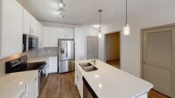 Located at 151 E Blount Ave in Knoxville, Tennessee, this single-floor residence offers a thoughtfully designed layout with modern finishes and a clean, contemporary aesthetic throughout. The open-concept kitchen serves as a central hub of the home, showcasing white shaker-style cabinetry, a subway tile backsplash, stainless steel appliances including a French door refrigerator, electric range, and microwave, along with a large center island featuring a double stainless steel sink and quartz countertops. Elegant pendant lighting illuminates the kitchen, which flows seamlessly into the living area, where wood-look flooring and a ceiling fan contribute to a comfortable ambiance. Natural light fills the space through large windows fitted with horizontal blinds. The bedrooms are carpeted and generously sized, each equipped with ceiling fans and bright windows that allow ample sunlight. The primary bathroom features a dual-sink vanity with quartz countertops, a tiled walk-in shower, and wood-look flooring. A secondary bathroom includes a tiled tub-shower combination, a single vanity, and coordinating finishes. An in-unit laundry area adds everyday convenience. The neutral color palette and consistent modern detailing create a cohesive, move-in ready living environment.