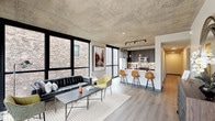Located in Chicago's vibrant West Loop neighborhood, this single-floor unit at 158 N Ada St showcases a compelling blend of industrial and contemporary design. The open-concept living and kitchen area is anchored by a striking exposed concrete ceiling that runs throughout, complemented by light hardwood-style flooring and floor-to-ceiling black-framed windows that flood the space with natural light and offer views of the surrounding urban streetscape.

The kitchen is thoughtfully designed with dark wood cabinetry, a decorative tile backsplash, stainless steel appliances, and a generous white waterfall-edge island with bar seating for three—illuminated by a trio of Edison-style pendant lights and a track lighting fixture above. The living area benefits from corner window placement, enhancing both light and openness.

The bedrooms continue the industrial aesthetic with exposed concrete ceilings and large black-framed windows providing natural light. One bedroom features direct access to an outdoor balcony. The bathrooms are finished in a clean, modern style with large-format white tile flooring, dark vanity cabinetry, LED-backlit mirrors, and matte black fixtures, with one bathroom offering a soaking tub and walk-in shower combination.