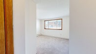 Located at 1631 Carl St in Lauderdale, Minnesota, this one-bedroom, one-bathroom unit offers a practical and well-organized single-floor layout. The kitchen is outfitted with warm honey-toned wood cabinetry, a subway tile backsplash, granite-look countertops, a double stainless steel sink, and light ceramic tile flooring that reflects natural light from the window. A wall-mounted air conditioning unit and baseboard heating ensure year-round comfort throughout the space. The kitchen opens into a living area that transitions seamlessly into the rest of the unit. The bedroom features soft wall-to-wall carpeting, a ceiling fan, a closet, and a window that allows natural light to fill the room. The full bathroom is finished with floor-to-ceiling cream ceramic tile surrounding a soaking tub and shower combination, complemented by a wood-trimmed vanity with an undermount sink and chrome fixtures. Crisp white walls and warm wood door and window trim carry through the unit, creating a cohesive and clean aesthetic. Baseboard heating is present throughout, adding to the unit's practical functionality. This unit is a straightforward and comfortable space suited for everyday living.
