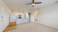 This single-floor, 2-bedroom, 1-bathroom unit offers a thoughtfully designed layout that maximizes functionality and comfort. The open-concept kitchen and living area serves as the heart of the home, featuring warm wood-look flooring, crisp white cabinetry, light quartz countertops, stainless steel appliances, and a central island with pendant lighting. A ceiling fan overhead and a door leading to the outdoors bring in natural light and airflow, making the living space feel bright and airy. The kitchen includes a dedicated pantry closet with wire shelving for additional storage.

Both bedrooms are carpeted and feature ceiling fans and windows that allow ample natural light. The spacious primary bedroom offers a comfortable footprint, while a large walk-in closet with multi-level wire shelving provides generous storage capacity.

The bathroom is finished with light wood-look flooring, a white shaker-style vanity, a gray countertop, and a well-lit mirror. A dedicated laundry area with utility hookups and overhead shelving adds everyday convenience. Throughout the unit, neutral tones, clean lines, and consistent modern finishes create a cohesive and welcoming ambiance suitable for a variety of lifestyles.