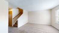 Located at 4333 Bayberry Cove in Bellbrook, Ohio, this two-story home offers a functional and straightforward layout across two levels. The main living area is generously sized, featuring neutral-toned carpet and a staircase with a wooden handrail leading to the upper floor, all beneath a textured ceiling. The galley-style kitchen is equipped with white cabinetry accented by wood-tone trim, a gas range, refrigerator, dishwasher, and a double sink positioned beneath a window that allows natural light in. The kitchen features durable hardwood-style flooring that extends into several other areas of the home. The bedrooms are comfortably sized — some with carpet and others with hardwood-style flooring — each offering neutral walls and natural light through windows fitted with blinds. The bathroom includes a vanity with storage, a tub-shower combination, toilet, and hardwood-style flooring. A dedicated utility room houses the water heater along with washer and dryer hookups, as well as overhead wire shelving for additional storage. The home's clean, neutral palette throughout provides a versatile canvas adaptable to a variety of interior styles.