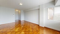 Located on the sixth floor at 825 New Hampshire Ave NW in Washington, DC, this one-bedroom, one-bathroom unit offers a well-organized layout across a single floor. Warm-toned parquet hardwood flooring runs throughout the living room and bedroom, adding a classic, polished character to the space.

The living room is bright and open, featuring a bank of large windows fitted with horizontal blinds that allow natural light to filter in while offering views of the surrounding cityscape and greenery. A stylish black-framed barn-style sliding door adds a modern, industrial touch and connects the living area to the bedroom.

The bedroom is a cozy, private retreat with its own window overlooking the neighborhood, continuing the parquet flooring and clean white walls found throughout the unit.

The kitchen is efficiently designed with light wood cabinetry, a stainless steel gas range, an under-cabinet range hood, and a single-basin stainless steel sink set into white quartz-style countertops. Light tile flooring keeps the space bright and easy to maintain.

The bathroom features clean white subway tile wainscoting, a mirrored medicine cabinet, and crisp white fixtures, lending a simple, functional aesthetic. A hallway connects the entry to the main living areas, completing this well-planned urban residence.
