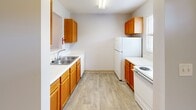 Located at 1830 20th Avenue Dr NE in Hickory, NC, this single-floor, one-bedroom, one-bathroom home offers a practical and well-organized layout. The galley-style kitchen is equipped with warm honey-toned wood cabinetry, white appliances including a refrigerator and electric range, a double-basin sink, and ample upper and lower cabinet storage. Light wood-look flooring runs through the kitchen and main living areas, contributing to a clean, cohesive aesthetic. The open doll's-eye view reveals a bright living area with a sliding glass door that invites natural light and outdoor views. The bedroom is a comfortable size, featuring soft wall-to-wall carpeting, a ceiling fan with light fixture, a window with natural light, and a sliding closet with wire shelving for organized storage. The bathroom includes a wood-toned vanity with a single sink, white countertop, a large mirror, additional medicine cabinet storage, and a well-lit vanity fixture above. Classic white mosaic tile flooring adds a timeless touch. A dedicated laundry area provides washer and dryer connections, including a dryer vent and electrical outlets, with wire shelving above. A hallway connects the rooms, completing this efficiently designed single-level home.