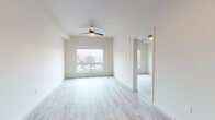 Located on the seventh floor at 3214 Broadway in Everett, WA, this modern unit offers a thoughtfully designed single-level layout with a bright, open-concept feel. Light-toned luxury vinyl plank flooring runs throughout, unifying the living, sleeping, and kitchen areas with a clean, cohesive aesthetic.

The kitchen is a standout feature, showcasing warm wood-grain flat-panel cabinetry extending from floor to ceiling, white quartz countertops, a subway tile backsplash, and a full suite of stainless steel appliances including a refrigerator, electric range, over-the-range microwave, and dishwasher. Recessed lighting and an open sightline to the living area make this an inviting and functional space.

The living and bedroom areas are generously proportioned, each featuring ceiling fans and large windows that allow abundant natural light and offer views of the surrounding Everett cityscape and open sky. The bedroom, visible from the doll's-eye floor plan view, is a well-defined private retreat with ample wall space.

The bathroom is finished with the same warm wood-grain cabinetry as the kitchen, paired with light stone-look tile flooring and accessible grab bars, combining practicality with modern style. The overall ambiance of the unit is clean, contemporary, and move-in ready.