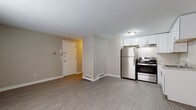 Located at 72 Edbert St in Chicopee, Massachusetts, this single-floor residence offers a practical and well-maintained layout suitable for everyday living. The open-concept living and kitchen area is finished with light gray wood-look flooring that extends throughout much of the unit, creating a cohesive and clean aesthetic. Neutral taupe walls provide a versatile backdrop throughout the space.

The kitchen is thoughtfully appointed with white shaker-style cabinetry, light granite-patterned countertops, a stainless steel refrigerator, and a stainless steel electric range with an overhead exhaust hood. A stainless steel sink completes the functional workspace, making the kitchen both practical and visually appealing.

The living area is open and airy, with baseboard heating running along the perimeter walls. A separate bedroom features soft gray carpeting, a window that allows natural light, and a wall-mounted air conditioning unit for climate control, along with baseboard heat.

The full bathroom includes a soaking tub with shower, toilet, and vanity, all finished with wood-look vinyl flooring that coordinates with the rest of the unit. The overall layout, as seen in the floor plan overview, is efficiently organized with a clear entry point and well-defined living zones.