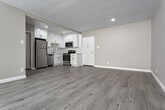 Located in the vibrant Los Feliz neighborhood of Los Angeles, this single-floor unit at 1840 Winona Blvd offers a clean, modern aesthetic throughout. The open-concept living area is anchored by light gray wood-style flooring that flows seamlessly throughout the space, complementing the neutral warm-gray walls and crisp white trim. Large sliding glass doors dressed with vertical blinds bathe the living room in natural light and provide direct access to a balcony, enhancing the sense of openness. A wall-mounted air conditioning unit adds convenient climate control to the main living area.

The kitchen is thoughtfully designed with bright white shaker-style cabinetry extending to the ceiling for ample storage, paired with light quartz countertops and a full suite of stainless steel appliances, including a refrigerator, electric range, microwave, and dishwasher. Recessed lighting illuminates the kitchen and adjacent dining area, creating a welcoming atmosphere.

The bedroom features a spacious closet with built-in shelving and organizational systems, offering generous storage. The bathroom is finished with clean white subway tile surrounding the soaking tub and shower combination, brushed nickel fixtures, and a crisp, minimalist design. Throughout, the unit presents a well-maintained, move-in-ready condition with a cohesive and contemporary feel.