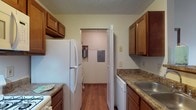 Located at 990 Plumway Ln in Lewis Center, Ohio, this single-floor residence offers a practical and comfortable layout designed for everyday living. The galley-style kitchen is well-appointed with warm wood cabinetry, dark granite-style countertops, hardwood-style flooring, and white appliances including a refrigerator, range, dishwasher, and over-the-range microwave. A pass-through opening connects the kitchen to the living area, creating an open and connected feel. The living area transitions between hardwood-style flooring and plush carpet, offering both comfort and functionality, with a private entry door providing convenient access. The bedrooms are carpeted and feature natural light from windows with blinds, textured ceilings, and closet storage — one bedroom includes a spacious walk-in closet with dual wire shelving systems for generous organization. The two full bathrooms each feature a tub/shower combo with stone-look countertops and hardwood-style flooring, providing a clean and cohesive aesthetic. A dedicated utility room houses the Rheem water heater and electrical panel, keeping mechanical systems neatly contained. The overall layout is efficient and well-organized, making this a functional single-level living space in Lewis Center.