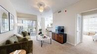 Located at 6228 Savannah Breeze Ct in Tampa, FL, this thoughtfully designed one-bedroom, one-bathroom residence offers a comfortable and efficient single-floor layout. The bright living room features soft carpet flooring, a ceiling light fixture, and a sliding glass door that opens to a private balcony with outdoor views, filling the space with natural light. The open-concept design connects the living area seamlessly to the dining space and kitchen, which is equipped with stainless steel appliances including a refrigerator, electric range with microwave overhead, and dishwasher. Light wood cabinetry and laminate flooring give the kitchen a clean, functional aesthetic. The spacious bedroom is a standout feature, highlighted by a bold navy accent wall, a ceiling fan, a large window with sheer curtains, and plush carpet flooring. Two closets provide ample storage. The bathroom includes a single-sink vanity with light wood cabinetry, a large mirror with overhead lighting, and a combination of wood-look and tile flooring. A dedicated laundry area and entrance hallway round out the layout, adding everyday convenience to this well-organized Tampa residence.