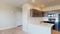 Located at 10115 Cherry Ln in Nampa, Idaho, this single-story home offers a well-designed, open layout that combines modern finishes with a clean, neutral aesthetic throughout. The living area is a standout, featuring soaring vaulted ceilings, a ceiling fan, and light wood-look flooring that extends seamlessly through the main areas. Large windows with blinds flood the space with natural light and provide pleasant outdoor views of the surrounding landscape. A glass-panel door connects the living area to the exterior, enhancing the bright and airy feel of the room. The kitchen is thoughtfully appointed with rich, dark shaker-style cabinetry, light quartz countertops, a stainless steel undermount sink, a built-in dishwasher, and a range, all set against crisp white walls and recessed lighting. A kitchen peninsula provides additional counter space and creates a natural flow into the adjoining living area. The bedrooms feature plush carpeting and generously sized windows that bring in ample natural light. The neutral color palette throughout the home creates a cohesive and inviting atmosphere, while the practical single-floor layout ensures ease of navigation between all living spaces.