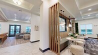 Located at 370 Homestead Ave in Greenwood, Indiana, this thoughtfully designed community clubhouse offers a comprehensive amenity experience across a single, generously sized floor. The grand entrance greets visitors with large-format marble-look tile flooring, soaring ceilings with a tray detail, and a striking multi-arm chandelier, establishing an upscale tone throughout.

The main living area transitions seamlessly into a lounge featuring slatted wood partitions, pendant lighting, and built-in bench seating, creating an inviting, modern aesthetic. A well-appointed kitchen showcases exposed wood beam ceilings, a marble-look island, deep teal subway tile backsplash, open shelving, and pendant lighting—designed for both function and style. An adjacent formal dining area provides a large communal table surrounded by ample natural light from multiple windows.

The fitness center is expansive and well-equipped, featuring a wood-paneled ceiling, bold green accent walls, ceiling fans, and a full suite of strength and cardio equipment. A secondary exercise and recreation room offers additional space for leisure, housing a billiards table and shuffleboard amid large windows with outdoor views. A separate lounge area features comfortable seating, large-screen TVs, a foosball table, and warm wood-toned wall accents, completing this multifaceted community hub.