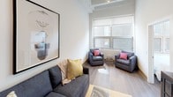 Located in Chicago's South Loop neighborhood, this single-floor unit at 150 E 11th Pl showcases a thoughtfully designed interior with notable architectural character. The living area immediately impresses with dramatically high ceilings featuring exposed beam detailing, globe pendant lighting, and wide-plank hardwood-style flooring that extends throughout the space. Large windows allow natural light to flow generously into the living and dining areas, which connect fluidly to create an open, airy layout well-suited for both relaxing and entertaining.

The kitchen is outfitted with contemporary wood-grain cabinetry extending to the ceiling, stainless steel appliances, white countertops, and a stainless sink — combining functionality with a clean, modern aesthetic. Multiple bedrooms offer comfortable accommodations, with some featuring large windows that look out to the urban surroundings. Both bathrooms are finished with floating wood-grain vanities, white countertops, undermount sinks, chrome fixtures, and full tub-shower combinations, delivering a cohesive and polished look throughout. The overall ambiance is modern and urban, balancing industrial loft-inspired details with refined contemporary finishes.