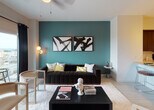 Located in the heart of West Palm Beach, FL, this stylish single-floor residence at 591 Evernia St offers a thoughtfully designed open-concept layout with contemporary finishes throughout. Bold teal accent walls create a striking visual identity in the living and dining areas, complemented by light wood-style flooring and crisp white ceilings that enhance the sense of openness and airiness.

The kitchen is a standout feature, outfitted with rich dark wood cabinetry, stainless steel appliances including a range, microwave, and refrigerator, a classic subway tile backsplash, and light stone countertops with a peninsula that flows seamlessly into the main living area. Pendant lighting adds a warm, modern touch overhead.

The living room is anchored by large sliding glass doors that open to a balcony, offering expansive city views of West Palm Beach. The bedroom is a serene retreat with soft neutral tones, a generous closet, and a large window framing elevated views of the surrounding cityscape. The bathroom features a clean, minimalist design with a tub-shower combination, large-format tile, and dark wood vanity cabinetry. An in-unit laundry area adds everyday convenience. The overall ambiance is modern, vibrant, and urban.