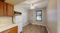 Located at 12 S Mill St in Pontiac, Michigan, this one-bedroom, one-bathroom unit offers a practical and efficient layout across a single floor. The combined kitchen, dining, and living area serves as the heart of the unit, featuring durable hardwood-style vinyl flooring, a ceiling fan with light fixture, and a window with blinds that brings in natural light. A cast-iron radiator provides heating. The kitchen is equipped with warm-toned oak cabinetry, a countertop with sink, a full-size refrigerator, and a microwave, offering functional storage and prep space.

The bedroom is carpeted for comfort and includes a ceiling fan, a window with natural light, a cast-iron radiator, and access to two closets, providing ample storage. The bathroom features classic penny-tile flooring, white subway tile surrounding a bathtub with shower curtain, a wall-mounted sink, a mirrored medicine cabinet, and a toilet — all in a clean, utilitarian layout.

This unit presents a straightforward, no-frills living space well-suited for a single occupant seeking a practical home in the Pontiac area.