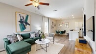 This single-floor residence offers a thoughtfully designed open-concept layout where the living, dining, and kitchen areas flow seamlessly together, all finished with durable wood-style flooring throughout. The living room is bright and welcoming, featuring a ceiling fan, large windows that invite natural light, and generous wall space ideal for artwork. It connects directly to a dedicated dining area, which benefits from its own oversized window with outdoor views and stylish pendant lighting overhead.

The kitchen is well-equipped with white shaker-style cabinetry, light quartz countertops, a classic subway tile backsplash, and a full suite of stainless steel appliances including a refrigerator with ice dispenser, electric range, and built-in microwave. A peninsula with seating provides additional prep and dining space.

A hallway leads to the bedroom, which is a comfortable and quiet retreat featuring a ceiling fan, a large window with outdoor views, and ample room for furnishings. An adjacent bathroom offers white vanity cabinetry and clean, neutral finishes.

A dedicated laundry area includes a full-size top-load washer and built-in wire shelving for organized storage, adding a practical and convenient touch to the overall layout.