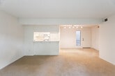 Located at 1201 Fairhaven Ave in Santa Ana, California, this single-story residence offers a well-organized, open-concept layout designed for comfortable living. The kitchen is a functional highlight, featuring white cabinetry, ample counter space, a double sink, a gas range, and a built-in microwave. A skylight overhead floods the space with natural light, creating a bright and inviting atmosphere. Dark hardwood-style flooring anchors the kitchen area, providing a clean contrast to the white cabinetry and countertops. The kitchen opens seamlessly into the main living area via a peninsula counter, ideal for casual dining or entertaining. The expansive living area is carpeted and bathed in natural light, courtesy of large sliding glass doors that frame views of lush greenery and a private outdoor patio. The bedroom is generously sized with plush carpeting, multiple louvered bi-fold closets offering abundant storage, and a window with garden views. A hallway bathroom with hardwood-style flooring provides convenience, accompanied by nearby built-in cabinetry for additional storage. Track lighting throughout the main living spaces adds a modern touch, while the textured ceilings and clean white walls maintain a neutral, move-in-ready aesthetic throughout.