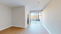 Located in the Los Feliz neighborhood of Los Angeles, this single-floor unit at 1800 N Normandie Ave offers a clean, modern aesthetic throughout. Light wood flooring flows seamlessly across the living areas, complementing the crisp white walls and bright, airy atmosphere created by abundant natural light.

The open living area is spacious and versatile, with neutral-toned walls, recessed lighting, and easy access to a private balcony through large sliding glass doors dressed with vertical blinds. The balcony frames pleasant views of mature trees, bringing a touch of greenery into the space.

The kitchen is well-appointed with stainless steel appliances, including a gas range, over-the-range microwave, and refrigerator. White cabinetry pairs with a subtle tile backsplash, creating a functional and contemporary cooking space.

A hallway connects the main living areas to the bedroom and bathroom. The hallway features built-in louvered closet doors and a mirrored sliding closet, providing generous storage. The bedroom is generously proportioned with continued light wood flooring and soft neutral tones. The bathroom includes a full tub-shower combination with classic chrome fixtures and a clean white finish. In-unit laundry with a stacked washer and dryer adds everyday convenience to this well-designed Los Angeles residence.