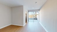 Located in the Los Feliz neighborhood of Los Angeles, this single-floor unit at 1800 N Normandie Ave offers a clean, modern aesthetic throughout. Light wood flooring flows seamlessly across the living areas, complementing the crisp white walls and bright, airy atmosphere created by abundant natural light.

The open living area is spacious and versatile, with neutral-toned walls, recessed lighting, and easy access to a private balcony through large sliding glass doors dressed with vertical blinds. The balcony frames pleasant views of mature trees, bringing a touch of greenery into the space.

The kitchen is well-appointed with stainless steel appliances, including a gas range, over-the-range microwave, and refrigerator. White cabinetry pairs with a subtle tile backsplash, creating a functional and contemporary cooking space.

A hallway connects the main living areas to the bedroom and bathroom. The hallway features built-in louvered closet doors and a mirrored sliding closet, providing generous storage. The bedroom is generously proportioned with continued light wood flooring and soft neutral tones. The bathroom includes a full tub-shower combination with classic chrome fixtures and a clean white finish. In-unit laundry with a stacked washer and dryer adds everyday convenience to this well-designed Los Angeles residence.