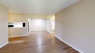 Located on Mercer University Drive in Macon, Georgia, this single-story home offers five bedrooms and two full bathrooms within a efficiently arranged floor plan. The interior maintains a consistent neutral color palette of warm beige tones complemented by wood-look vinyl flooring in the common areas and hallways, while the bedrooms feature plush carpeting with ceiling fans for added comfort.

The kitchen is laid out in a galley style, featuring white cabinetry with light countertops, black appliances including a refrigerator and dishwasher, and a stainless steel sink. It connects directly to the combined living area, which benefits from a sliding glass door that allows natural light to filter through vertical blinds. An open passage links the kitchen and living spaces seamlessly.

Both bathrooms are finished with full tub-shower combinations equipped with grab bars and wood-look flooring, maintaining a clean, functional aesthetic. A dedicated laundry room includes built-in shelving and washer/dryer hookups. Hallways connect the various bedrooms efficiently throughout the layout. The textured ceilings appear consistently across the home, contributing to a cohesive interior character throughout.