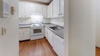 Located at 90 Powers St in Milford, New Hampshire, this single-floor unit offers a clean, functional layout designed for comfortable everyday living. The open living area features warm wood-style laminate flooring and neutral-toned walls beneath a textured ceiling, creating a bright and welcoming atmosphere. A closet is conveniently situated near the entryway, providing practical storage from the moment you walk in. The kitchen is efficiently arranged with white cabinetry, gray speckled countertops, a tiled backsplash, and white appliances including a range and refrigerator, all set over matching wood-style flooring. The bedrooms are carpeted in neutral tones and receive natural light through windows fitted with blinds; baseboard heating ensures year-round comfort. Each bedroom includes closet space, with one featuring a full sliding-door closet. The bathroom is finished with white square wall tiles, a vanity with gray speckled countertops, white cabinetry, and light tile flooring, complemented by a large mirror. Throughout the unit, the consistent use of neutral colors and clean finishes contributes to a cohesive and move-in-ready aesthetic, well-suited for a range of living arrangements.