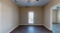 Located at 4750 Mac Rd in Valdosta, Georgia, this single-floor residence offers a well-designed layout with consistent, modern finishes throughout. Dark hardwood-style flooring runs across the living areas, bedrooms, kitchen, and bathrooms, providing a cohesive and polished aesthetic.

The open living area is bright and welcoming, featuring a ceiling fan and a glass-panel door that invites natural light and provides outdoor access. The space flows seamlessly toward the kitchen, which is a standout feature of the home. Crisp white shaker-style cabinetry reaches toward the ceiling, complemented by marble-look countertops and a full suite of stainless steel appliances, including a refrigerator, range, microwave, and dishwasher.

The bedrooms are generously proportioned, each equipped with ceiling fans and windows that allow for ample natural light and exterior views. The primary bedroom includes direct access to a private en-suite bathroom, along with a dedicated closet.

Both bathrooms are finished with white vanity cabinetry, marble-look countertops, large mirrors, and tub-shower combinations, maintaining the home's clean and contemporary character. The consistent warm-toned walls and bright white trim throughout contribute to an inviting and move-in-ready atmosphere.