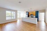 This well-appointed two-bedroom, three-bathroom residence in Haverhill, MA offers a thoughtfully designed open-concept layout with modern finishes throughout. The heart of the home is a spacious combined kitchen and living area bathed in natural light from large windows. The kitchen is a standout, featuring a generous white quartz island with an undermount sink, bold navy cabinetry paired with warm wood-toned uppers, a subway tile backsplash, stainless steel appliances, and globe pendant lighting that adds a contemporary touch. Rich light oak hardwood flooring flows throughout the main living areas, creating a warm and cohesive aesthetic. Both bedrooms are carpeted and filled with natural light from multiple windows, offering a comfortable and quiet retreat. The three bathrooms are clean and modern, with one featuring a soaking tub with tiled surround and white quartz vanity, and another with a walk-in shower. A versatile den provides additional flexible living space, while three closets offer ample storage. The dedicated laundry room houses a full-size side-by-side washer and dryer. A private balcony rounds out this residence, providing an outdoor retreat. The overall ambiance is bright, modern, and move-in ready.