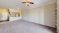 Located at 19800 Atascocita Shores Dr in Humble, TX, this 2-bedroom, 2-bathroom single-story home offers a comfortable and functional layout designed for everyday living. The spacious living room is a standout feature, boasting crown molding, plush carpeting, a ceiling fan, and built-in shelving along one wall. A sliding glass door leads to a private balcony, filling the room with natural light and providing outdoor access. The living area flows seamlessly into the kitchen via an open pass-through, where light wood cabinetry, laminate countertops, wood-look flooring, and a full suite of white appliances—including a refrigerator, electric range, microwave, and dishwasher—create a practical and tidy cooking space. Both bedrooms feature soft carpeting, ceiling fans, and ample natural light from large windows, with dedicated closets providing generous storage. The primary bedroom includes a built-in vanity area for added convenience. The two bathrooms each offer a tub-shower combination with tiled surrounds—one accented with a bold black tile border, the other with neutral beige tiling—complemented by wood-look flooring. Two hallways connect the spaces, enhancing the home's efficient and well-organized flow throughout.