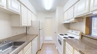 This single-floor unit offers a well-organized layout designed for comfortable everyday living. The galley-style kitchen is efficiently arranged with white cabinetry lining both sides, granite-style countertops, a full suite of white appliances including a refrigerator, electric range, and dishwasher, and a stainless steel sink. Light tile flooring and a window with blinds keep the kitchen bright and practical.

The living area is generously proportioned, featuring light tile flooring, warm neutral-toned walls, a ceiling fan with light fixture, and a sliding glass door that opens to an outdoor balcony, allowing natural light to flow in. The space offers a versatile, open feel well-suited for both relaxing and entertaining.

The bedrooms are comfortably sized with matching tile flooring, neutral walls, and windows fitted with blinds that provide natural light and privacy. Both bathrooms follow a consistent design theme, each featuring a tub and shower combination with white tile surround, a toilet, vanity with granite-style countertop, and a large mirror. The overall aesthetic throughout the unit is clean and cohesive, with a neutral color palette and tile flooring that creates a bright, low-maintenance living environment.
