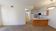Located at 2450 Airport Rd in Longmont, Colorado, this single-floor residence offers a practical and comfortable layout designed for everyday living. The kitchen is a functional centerpiece, featuring white cabinetry with warm wood-tone trim, a full suite of appliances including a refrigerator, electric range, built-in microwave, and dishwasher, as well as a peninsula with a double stainless steel sink that provides additional counter space and opens toward the living area. The open connection between the kitchen and the carpeted living space creates a cohesive flow throughout the main area, which is bright and neutrally finished with white walls. A pendant light fixture highlights the entryway, which includes tiled flooring and closet storage. The bedroom is well-proportioned with plush carpeting and a large window that frames views of the landscaped outdoor greenery, filling the room with natural light. The bathroom is cleanly appointed with tile flooring, a full soaking tub with a tiled surround and shower rod, and a vanity area. A fireplace is visible in the living room from the overhead floorplan view, adding a cozy focal point to the space. The overall aesthetic is clean, neutral, and move-in ready.