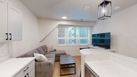 Located at 505 S Fifth St, Unit 209 in Champaign, Illinois, this one-bedroom, one-bathroom unit offers a thoughtfully designed layout with modern finishes throughout. The open-concept living and kitchen area serves as the heart of the unit, where sleek gray shaker-style cabinetry, a white quartz peninsula with bar seating, stainless steel appliances, and a classic subway tile backsplash come together to create a functional and stylish space. Pendant lantern lighting adds a contemporary touch above the peninsula, while recessed ceiling lights brighten the entire area. The living space comfortably accommodates seating and a dining area, creating an inviting atmosphere for everyday living. Warm hardwood-style flooring flows seamlessly throughout the unit, tying each room together with a clean, cohesive look. The bedroom offers a comfortable footprint with a large sliding closet featuring craftsman-style panel doors, a dedicated study nook, and natural light from a window. The bathroom is finished with a gray vanity with a white countertop, a framed mirror with modern lighting, black hardware accents, and a glass-enclosed walk-in shower, all set on the same warm hardwood-style flooring. This unit delivers a modern, move-in-ready living experience in the heart of Champaign.