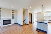 This contemporary multi-floor residence is designed with a clean, modern aesthetic throughout its three levels. The main living area centers around an open-concept layout where the kitchen flows seamlessly into the living room. The kitchen is outfitted with white shaker cabinetry, granite countertops, stainless steel appliances including a French door refrigerator and range, a patterned tile backsplash, and a central island with pendant globe lighting overhead. The living room features light hardwood-style flooring, a built-in fireplace flanked by open shelving, and a sliding glass door that invites natural light and outdoor access.

Bedrooms are carpeted and generously windowed, offering views of the surrounding neighborhood and filling the rooms with natural light. A ceiling fan provides additional comfort. The bathrooms are well-appointed, featuring granite-topped white vanities, large mirrors, brushed gold fixtures, and subway tile surrounds in the tub-shower combinations. Hardwood-style flooring carries through the bathroom spaces for a cohesive look.

Additional highlights include a dedicated in-unit laundry area with a full-size washer and dryer, a walk-in closet with wire shelving, and recessed lighting throughout. The overall ambiance is bright, clean, and move-in ready.