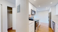 Located at 1000 Brunette Ave in Coquitlam, BC, this one-bedroom, one-bathroom unit offers a well-designed layout that maximizes its compact footprint. Warm hardwood-style flooring runs throughout, creating a cohesive and inviting atmosphere from room to room.

The kitchen has been thoughtfully updated with sleek, high-gloss white cabinetry extending to the ceiling for ample storage, stone-look countertops, and a full suite of stainless steel appliances including a refrigerator, electric range with over-the-range microwave, and dishwasher. Recessed lighting adds a clean, modern touch.

The open-concept living area is bright and airy, featuring a large sliding glass door that leads to a balcony and frames expansive outdoor views of the surrounding greenery and cityscape beyond — an ideal space for relaxing or entertaining.

The bedroom is a comfortable size, benefiting from its own window with similarly scenic views and a baseboard heating system. A hallway connects the bedroom to the rest of the unit, providing a sense of separation and privacy.

The bathroom is finished with a white vanity, granite-style countertop, undermount sink, large mirror, and a glass-enclosed shower, presenting a clean and contemporary aesthetic throughout.
