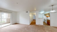 This single-floor, three-bedroom, two-bathroom home in Vallejo, California offers a well-organized and functional layout across a comfortable footprint. The living room is bright and open, featuring warm beige carpeting and a sliding glass door with vertical blinds that leads to a private balcony, filling the space with natural light and outdoor views. Adjacent to the living area, the galley-style kitchen is efficiently designed with warm wood cabinetry lining both sides, white countertops, hardwood-style flooring, and white appliances including a gas range and refrigerator. Each of the three carpeted bedrooms provides a calm, neutral environment with white walls, natural light from windows, and ample storage via sliding-door closets. The primary bedroom features a dedicated closet with built-in wire shelving for additional organization. Both bathrooms are finished with tile flooring, wood-toned vanities, and full tub-shower combinations. A dedicated closet space with wire shelving adds further storage utility. Throughout the home, a clean, neutral palette and consistent finishes create a cohesive and move-in-ready atmosphere.