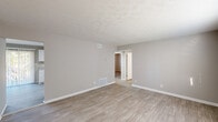 This single-floor, 2-bedroom, 1-bathroom residence offers a clean, functional layout with consistent neutral tones and updated finishes throughout. The living room features light wood-look flooring, soft gray walls, textured ceilings, and a window that brings in natural light — creating a bright and welcoming entry point to the home. The kitchen is well-equipped with white shaker-style cabinetry, granite-look countertops, and white appliances including a gas range, dishwasher, and refrigerator. A sliding glass door with vertical blinds opens to an outdoor view, filling the kitchen with additional natural light. Both bedrooms are carpeted for comfort and equipped with ceiling fans. Each bedroom includes a closet — one featuring a bifold double-door closet and the other a reach-in closet with shelving. The bedrooms share convenient access to the full bathroom, which includes a tiled tub/shower combination, white vanity, and a window for natural ventilation. Light wood-look flooring runs through the main living areas, tying the space together with a cohesive, contemporary feel. The overall design is clean, neutral, and move-in ready.