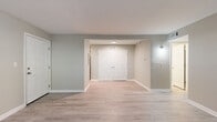 This single-floor unit offers a thoughtfully designed layout with a cohesive, updated aesthetic throughout. Light wood-look luxury vinyl plank flooring runs continuously across the living areas, bedrooms, and hallways, creating a seamless and contemporary feel. Neutral greige-toned walls complement the bright white baseboards and trim found in every room.

The open living area is spacious and well-lit, featuring a structural beam detail along the ceiling and access to additional rooms via a central hallway. A secondary living or flex space includes a set of double doors, providing versatile storage or utility options. The kitchen is equipped with white shaker-style cabinetry, marble-look countertops, and stainless steel appliances including an electric range and over-the-range microwave.

The bedrooms are generously sized, each featuring windows that allow natural light and views of surrounding greenery, with textured ceilings adding subtle character. At least one bedroom includes a full-width double closet for ample storage. The bathroom features a white vanity with brushed nickel hardware and a full tub-shower combination, maintaining the unit's clean, modern finish throughout.