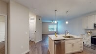 This single-story unit in Panama City Beach, Florida, offers a thoughtfully designed open-concept floor plan that maximizes functionality and flow. The living area features wood-look flooring, neutral walls, a ceiling fan, and a window that allows natural light to filter in, creating a bright and comfortable atmosphere.

The kitchen serves as the centerpiece of the main living space and is outfitted with white shaker-style cabinetry, granite countertops, and a gray subway tile backsplash. Stainless steel appliances include a French door refrigerator with ice maker, a range, a built-in microwave, and a dishwasher. A central island with an undermount sink and pendant lighting above provides additional prep space and casual seating potential.

The bedroom is generously sized, featuring plush carpeting, a ceiling fan, and a window with blinds. It connects directly to the full bathroom, which includes a soaking tub with subway tile surround, a granite-topped vanity, wood-look flooring, and a dedicated closet nearby.

Throughout the unit, consistent finishes—including neutral paint tones, clean trim work, and coordinated hardware—contribute to a cohesive and modern aesthetic well-suited for comfortable Florida living.